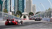 Open-wheel racecars on temporary street circuit through cityscape