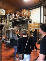 Group inside winery production area with barrels and stainless steel tanks
