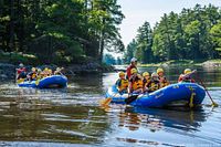 Family group rafting on calm section of river in blue Wilderness Tours raft