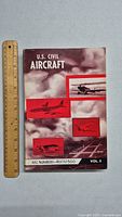 Front cover of the 1960s U.S. Civil Aircraft book with red aircraft images and title.