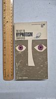 Front cover of the book showing the title, author, and graphic design featuring purple eyes and white nose on gray background next to a ruler measuring about 7 inches.