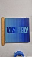 Front cover of the Vasarely art book showing blue gradient title and size reference with ruler.