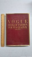 Front cover of the large hardcover book titled 'Vogue Book of Fashion Photography 1919-1979' in maroon and gold text, with a ruler next to it to show size.