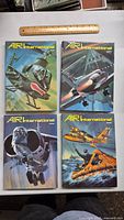 Four Air International hardcover magazines with aviation-themed illustrated covers including helicopters, jets, and rescue craft, laid out on a surface next to a 12-inch ruler for scale.