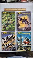 Four Air International hardcover volumes 28-31 with illustrated military aircraft covers and a wooden ruler for scale.