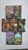 Front cover view of seven hardcover Arkham Horror books showing cover art and titles