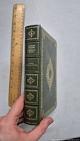 Front cover and spine of the green leather-bound Charles Dickens Great Expectations centennial edition book shown next to a ruler for size reference.