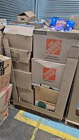 Medium size Home Depot box packed with various boxes and other items with some books visible on top