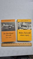 Two hardcover books, 'De Havilland Aircraft since 1909' and 'Miles Aircraft since 1925,' shown side by side with a ruler for size reference.