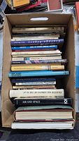 Photo showing a top view of the box filled with vintage aviation books featuring various spine titles and different book thicknesses and colors.