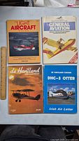 Four vintage aviation books laid out flat with a ruler for size reference. Titles and cover images clearly visible.