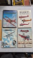 Four vintage aviation-themed hardcover books displayed on a table with a ruler for scale.