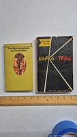 Front cover of two vintage Franz Kafka books, The Metamorphosis and The Trial, with ruler for size reference.