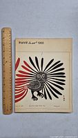 Front cover of the vintage Inuit art book showing traditional indigenous bird art with black and red feathers, ruler placed next to it for size reference.