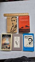 Top view of six vintage poetry books arranged side-by-side featuring classic poets Wordsworth, Spenser, Keats, Pound, and Donne with a ruler for scale.