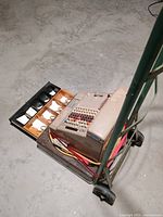 Side angle of the antique NCR cash register showing the open cash drawer with compartments and the body with keys and cranks.