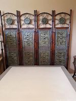 Front view showing full length of the four connected panels with embossed elephant metal decorations and circular metal medallions at top.