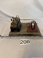 Front side view of the brass boiler and steam engine model with ruler for scale showing approximately 10 inch length.