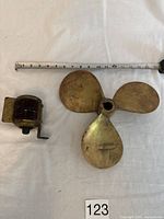 Photo showing both the solid brass marine propeller and the brass marine light with measuring tape for size reference.