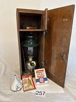 Vintage Coleman metal lantern inside a wooden box, with Mantles package and funnel on the side.