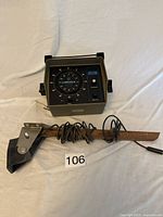 Vintage Lowrance Bluewater fish finder control unit and transducer mounted on wooden stick with cable.