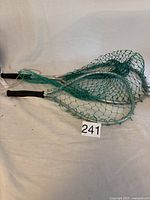 Two small fishing nets with green mesh, black grip handles, and aluminum frames placed side by side with lot number 241