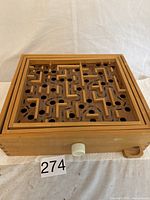 Wooden marble maze game box with carved maze top and white tilt knob.