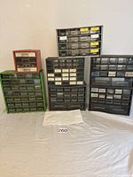 Six empty plastic parts drawer organizers in green, black, and red frames, assorted sizes, all with multiple clear plastic drawers mostly with label holders.