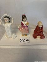 Photo showing all three Royal Doulton figurines together on a white surface.