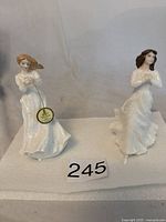 Two Royal Doulton porcelain figurines on white cloth background, showing full front and side views.