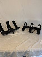 Two sets of black Scotty fishing rod holders with three holders each, shown lying on a flat white surface.