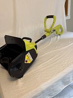 Side angle view of the full snow shovel showing telescopic handle and snow clearing scoop with safety label.