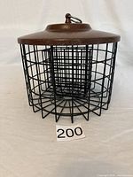 Front view of the suet feeder showing wire mesh cage and brown metal lid.