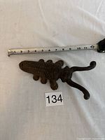Top view of the vintage cast iron boot jack next to a measuring tape showing about 10 inches in length.