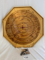 Overhead view of octagonal vintage Crokinole board and bag of playing pieces on white background.