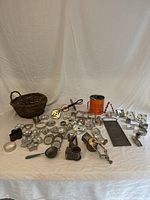 Top-down view of all vintage kitchen tools arranged on white cloth showing cookie cutters, grater, beater, sifter, and basket.