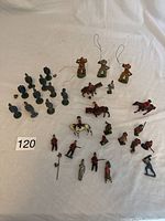 Overview of collection of small vintage figure toys including soldiers, horse riders, and cowboys, with some horses and some disassembled parts visible.