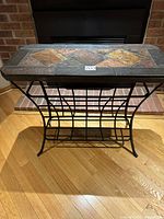 Front view of slate top wine rack showing multi-colored tile inlay and black metal frame.