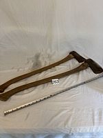 Two wood chopping tools on white cloth with measuring tape showing length