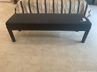 Front view of the black padded leatherette bench seat showing full length and legs.