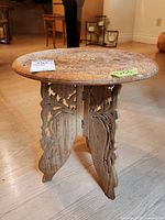 Front side view showing carved floral pattern and folding legs