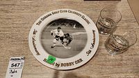 Collector plate with hockey image and lettering, accompanied by two Jack Daniel's glasses on a wooden surface.
