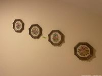 Four framed octagonal cross stitch floral artworks hung on a wall