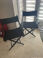 Two black folding canvas director's chairs side by side showing overall condition and design.
