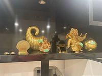 Photo showing brass Asian shoe ashtrays, cornucopia with baby figurine, shell decor, brass angel figurine with lyre, and a small brass basket.