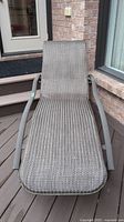 Front view of metal framed lounge chair with mesh body, showing fabric texture and armrests.