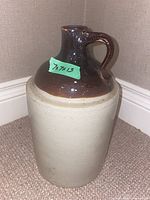 Side view of vintage Medalta stoneware jug showing brown glazed top and handle with unglazed base.