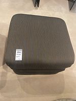 Top view showing square top with brown and black vertical striped fabric upholstery.