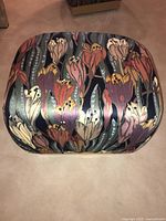 Top view of the floral patterned ottoman seat showing multicolored large flowers and leaves upholstery.