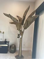 Full view of the fabricated metal palm tree sculpture with large textured leaves and metal parrot detail